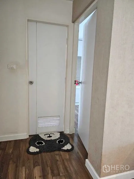 Condominium for sale in Watthana, Bangkok - Hallway with white doors and warm wood flooring inside the condominium.