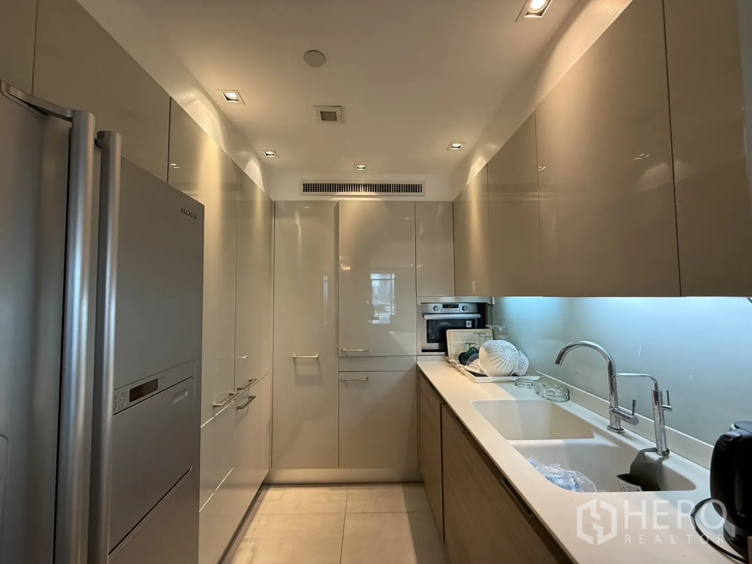 公寓 出租在Phaya Thai, Bangkok - 走廊式厨房，双水槽、嵌入式烤箱与亮面柜体。
