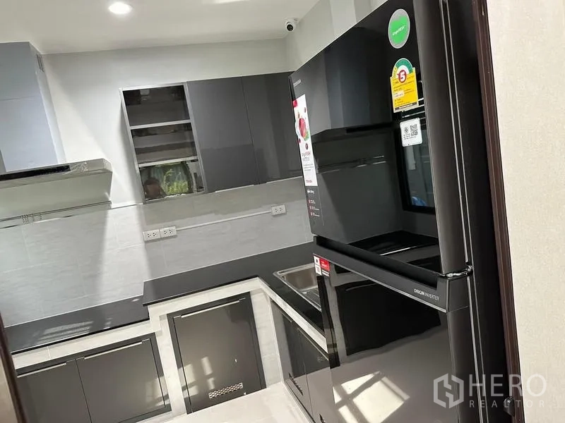 Detached House for sale in Saphan Sung, Bangkok - Fully fitted U-shaped kitchen with glossy cabinets and black refrigerator.