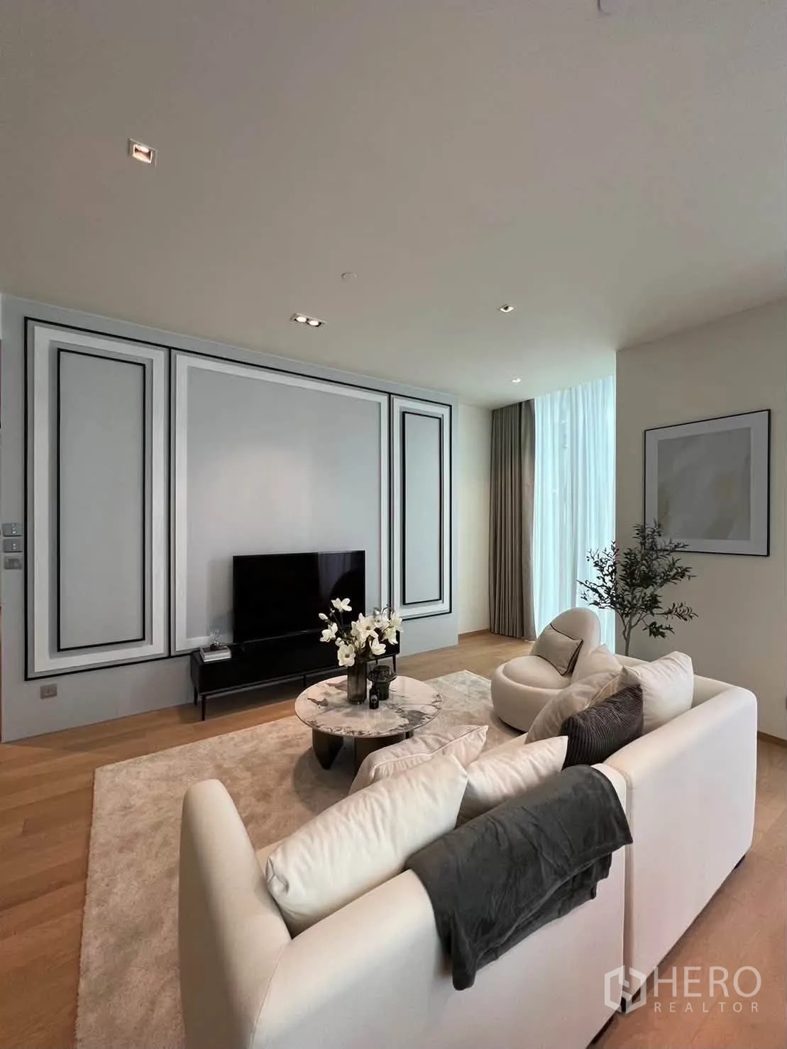 Condominium for rent in Pathum Wan, Bangkok - Living room wall with decorative molding, sofa set, and round marble coffee table.
