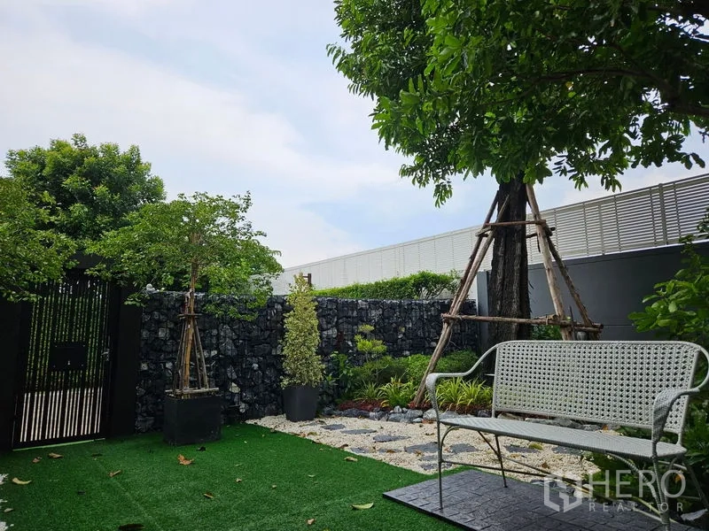 独立式住宅 出售在Thawi Watthana, Bangkok - 前庭花园，人工草坪、长椅与树木及石墙门。