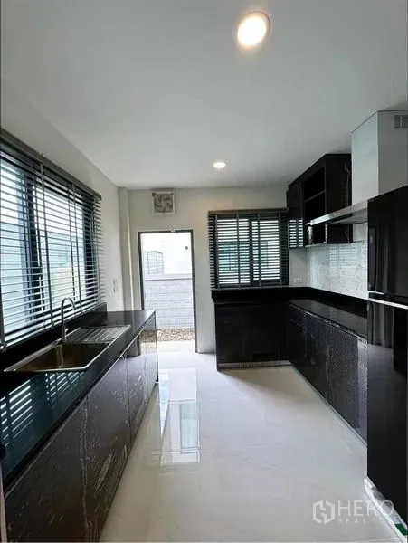 独立式住宅 出租或出售在Bang Phli, Samut Prakan - 封闭式厨房，黑色石材台面与充足柜体和采光。