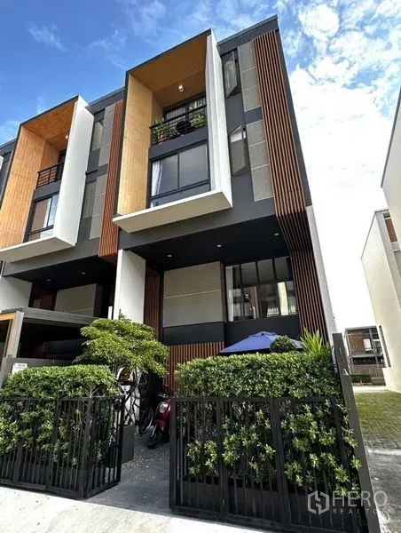Townhouse for rent in Suan Luang, Bangkok - Modern three-story townhouse facade with wood accents, large windows, and a small gated garden in Suan Luang.