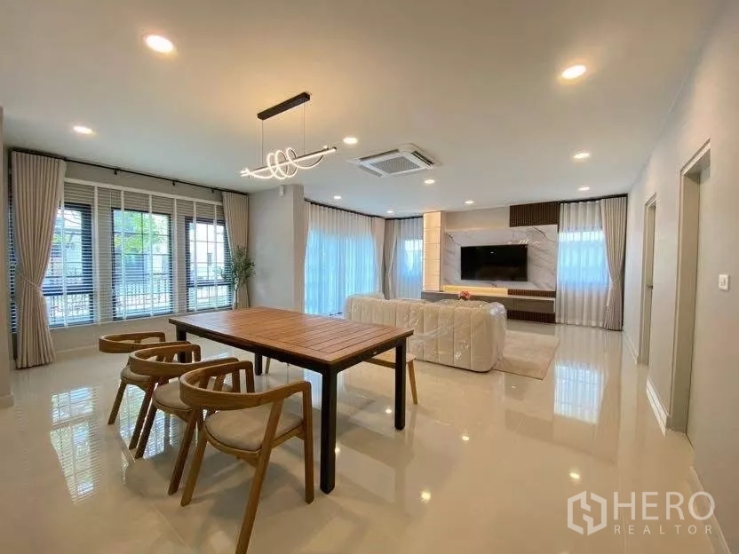 Detached House for rent in Bang Phli, Samut Prakan - Dining area with wooden table, designer chandelier and wide corner windows.