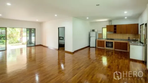 Detached House for sale in Bang Lamung, Chon Buri - L-shaped European kitchen with built-in oven beside a large living space and sliding doors.