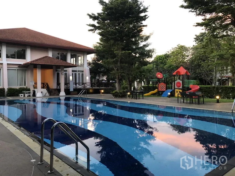 Detached House for rent in Wang Thonglang, Bangkok - Community swimming pool beside a clubhouse with trees and a children’s playground in the estate.