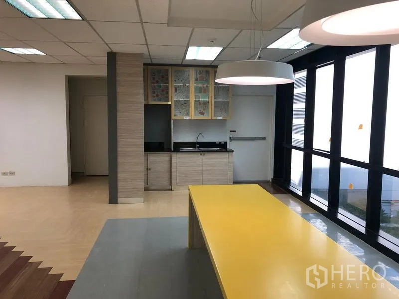 Office Space for rent in Bang Na, Bangkok - Pantry area featuring a long yellow island table, sink and tall windows for natural light.