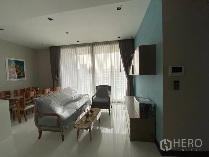 Condominium for rent in Khlong Toei, Bangkok - Open living and dining area with sofa set and full-height curtains overlooking the Bangkok skyline.