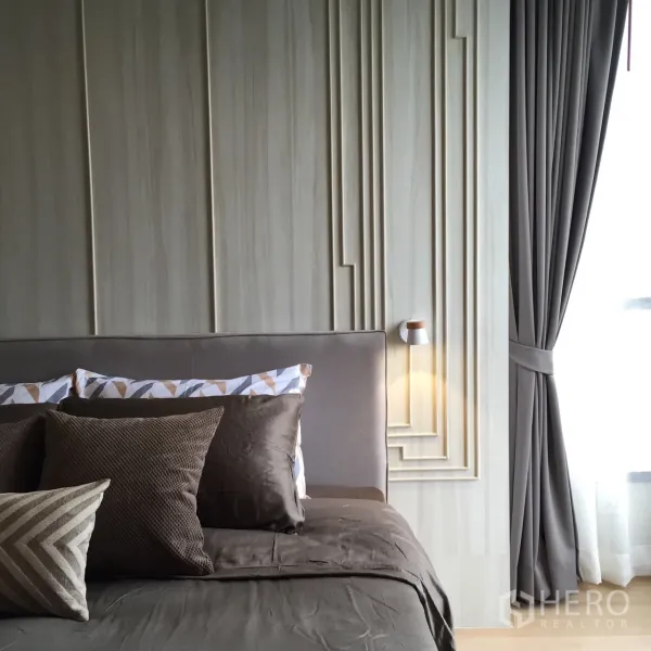 公寓 出租或出售在Watthana, Bangkok - 温馨主卧，立体装饰墙、棕色床品、壁灯与带纱帘的大窗。