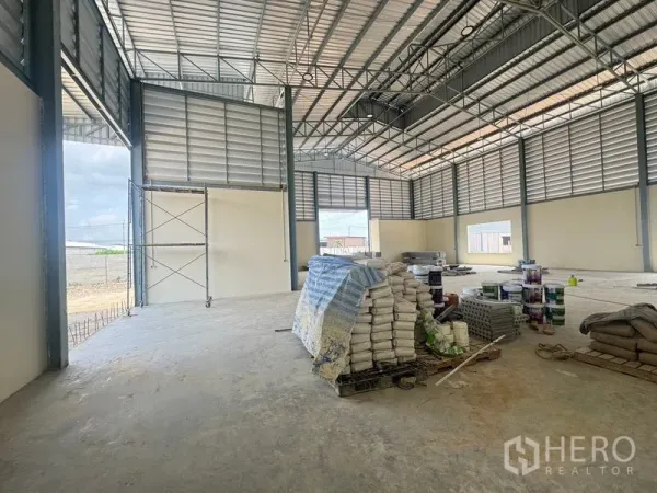 Warehouse for rent in Mueang Samut Prakan, Samut Prakan - Spacious warehouse interior with high ceiling, steel trusses, and large door openings.