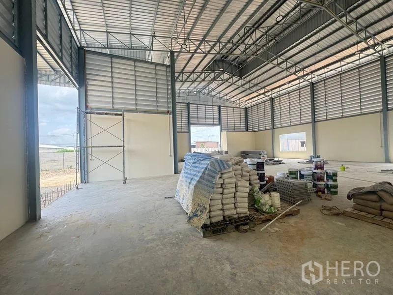 Warehouse for rent in Mueang Samut Prakan, Samut Prakan - Spacious warehouse interior with high ceiling, steel trusses, and large door openings.