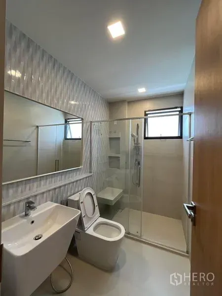 Detached House for rent or sale - Bright bathroom with textured wall tiles, wide mirror, and glass-enclosed shower with window.