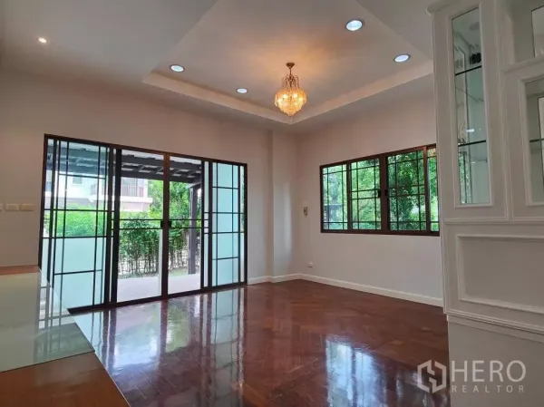 独立式住宅 出租或出售在Mueang Nonthaburi, Nonthaburi - 客厅采光充足，拼花木地板，水晶吊灯与大滑动玻璃门。
