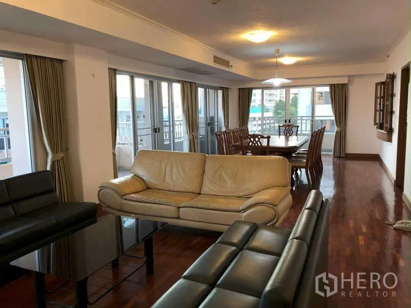 คอนโด ให้เช่าในSathon, Bangkok - ห้องนั่งเล่นและรับประทานอาหารแบบโอเพนพร้อมโซฟาหนัง พื้นไม้ และประตูกระจกออกสู่ระเบียงในคอนโดสาทร