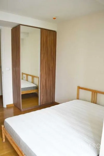 公寓 出租在Watthana, Bangkok - 舒适次卧一角，木床与镜面衣柜。