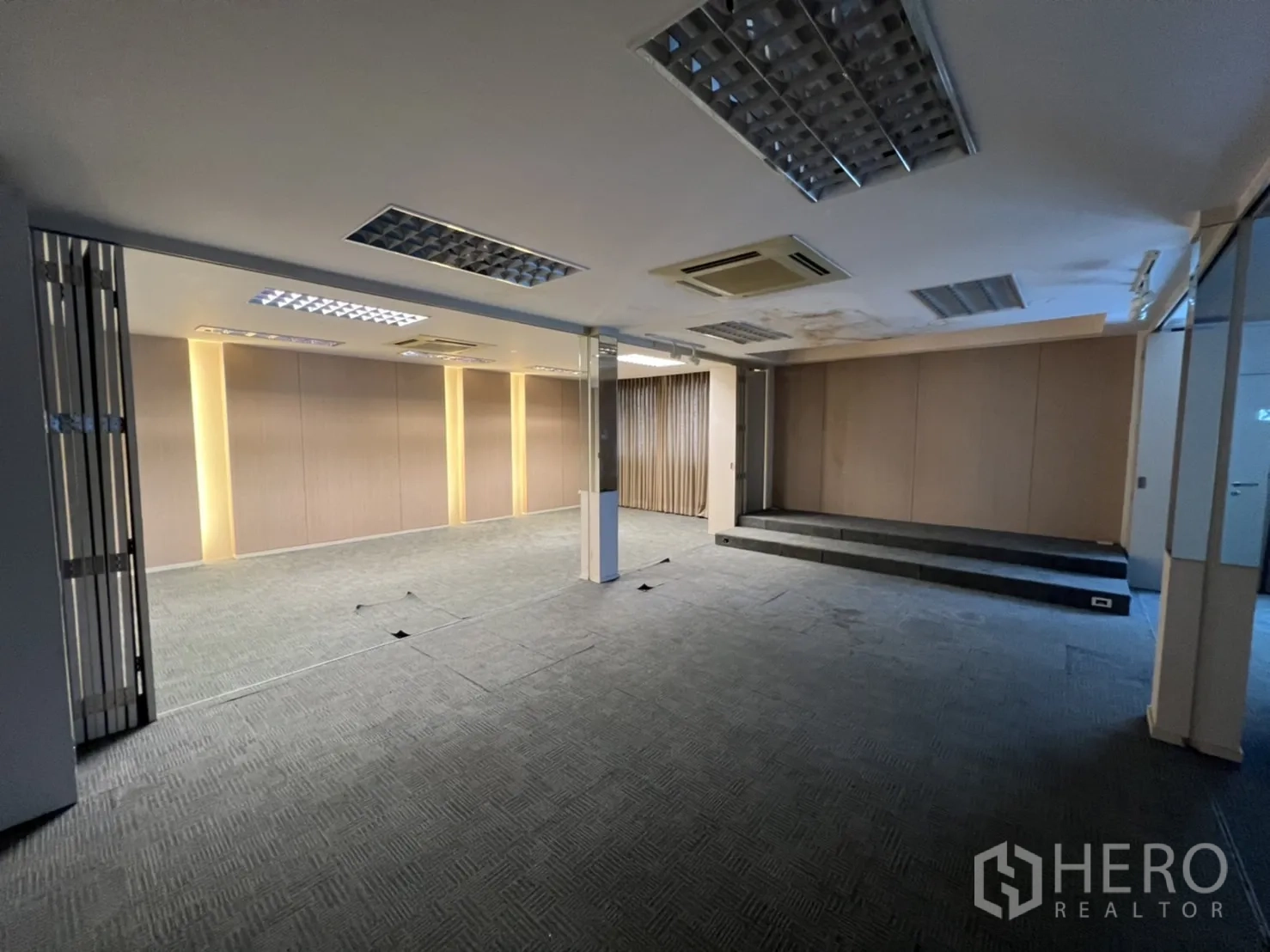 Shophouse for rent or sale in Watthana, Bangkok - Spacious office floor with carpet tiles, a small stage and downlights.