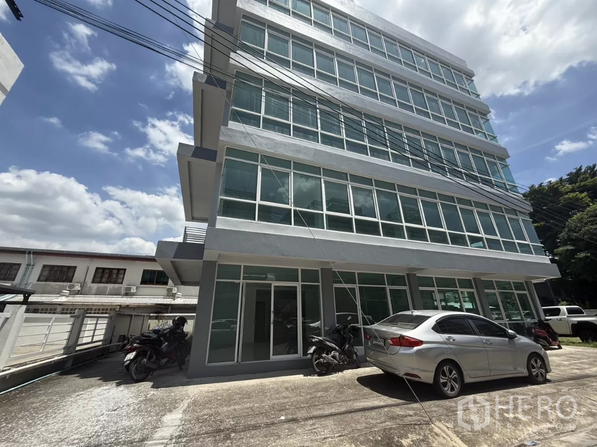 办公空间 出租在Bueng Kum, Bangkok - 现代办公楼侧立面，可见多层结构与车道停车区