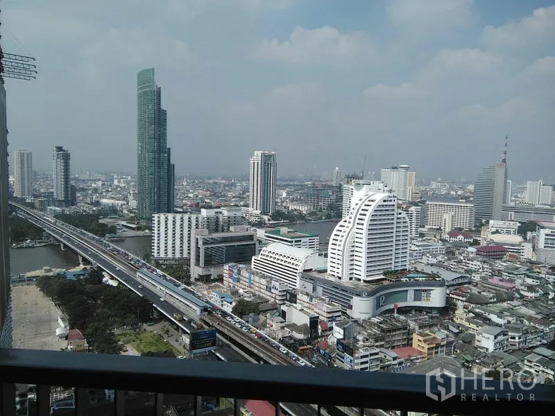 Condominium for rent in Sathon, Bangkok - High-floor balcony view of BTS line, city towers and the Chao Phraya River.