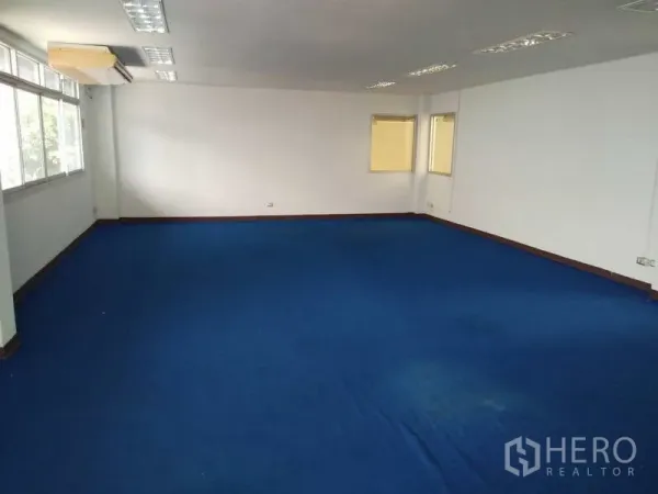 货栈 出租在Bang Phli, Samut Prakan - 宽敞办公室区域，蓝色地毯与多组顶灯及墙面窗户。