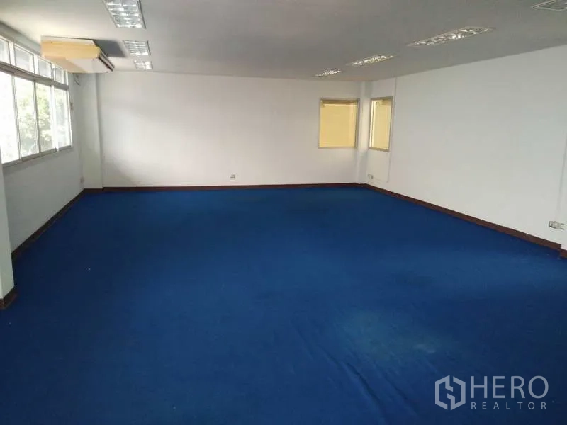 货栈 出租在Bang Phli, Samut Prakan - 宽敞办公室区域，蓝色地毯与多组顶灯及墙面窗户。