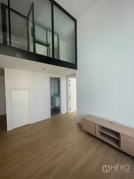 Condominium for rent in Khlong Toei, Bangkok - Loft mezzanine with glass enclosure above the high-ceiling living area.