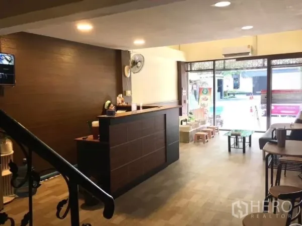 Shophouse for rent in Watthana, Bangkok - Ground‑floor reception with wooden counter, seating and glass frontage.