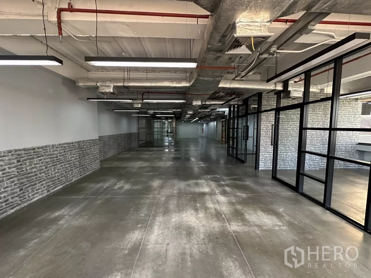 办公空间 出租 - 办公走廊，黑色框架玻璃隔间与砖纹墙面。