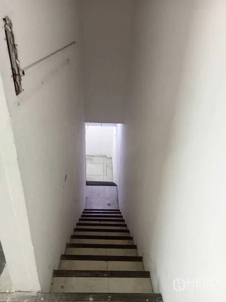 Retail Space for rent in Watthana, Bangkok - Internal staircase leading to a lower level within the retail unit, with white walls and tiled steps.