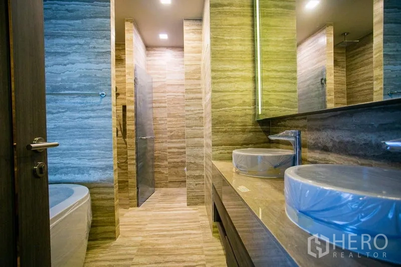 Condominium for rent in Watthana, Bangkok - Spacious master bathroom with double vanity, walk-in shower, and bathtub in stone finish.