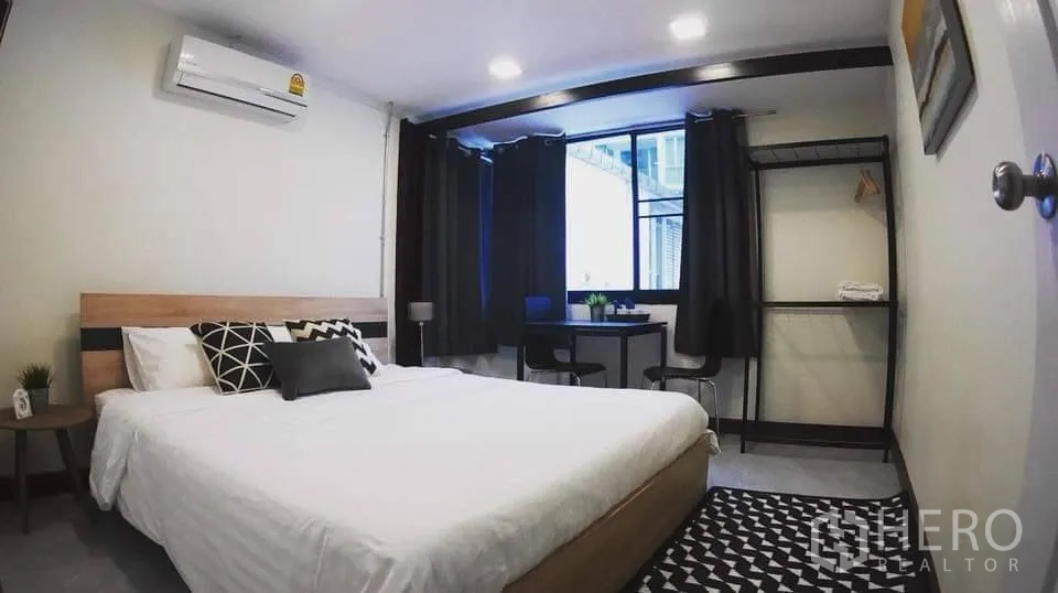 Detached House for rent in Watthana, Bangkok - Bright bedroom with double bed, window, desk, open wardrobe rack, and air-conditioning.