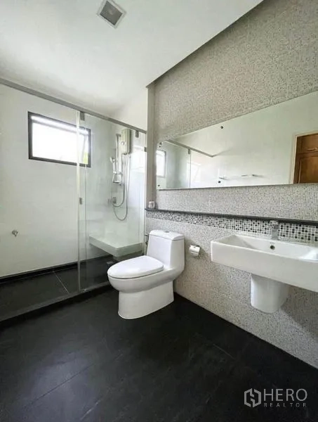 Detached House for rent in Prawet, Bangkok - Contemporary bathroom featuring a glass shower enclosure, long mirror and white sanitary ware.