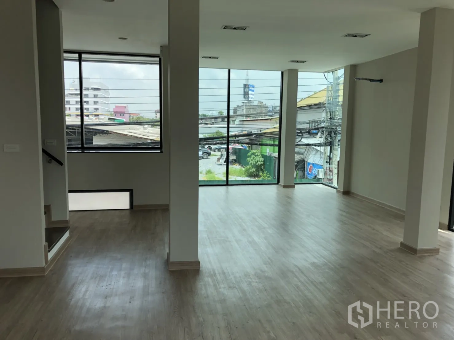 Townhouse for rent in Din Daeng, Bangkok - Bright open-plan living area with light wood floors and large corner windows in a Huai Khwang townhouse.