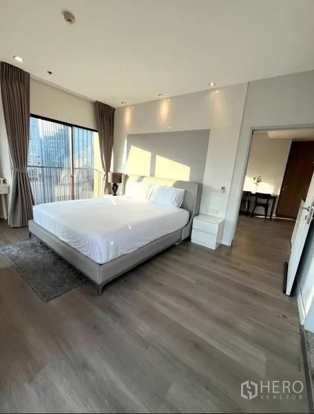 Condominium for rent in Bangkok - Spacious bedroom with king bed, wood flooring and tall corner windows overlooking the city.