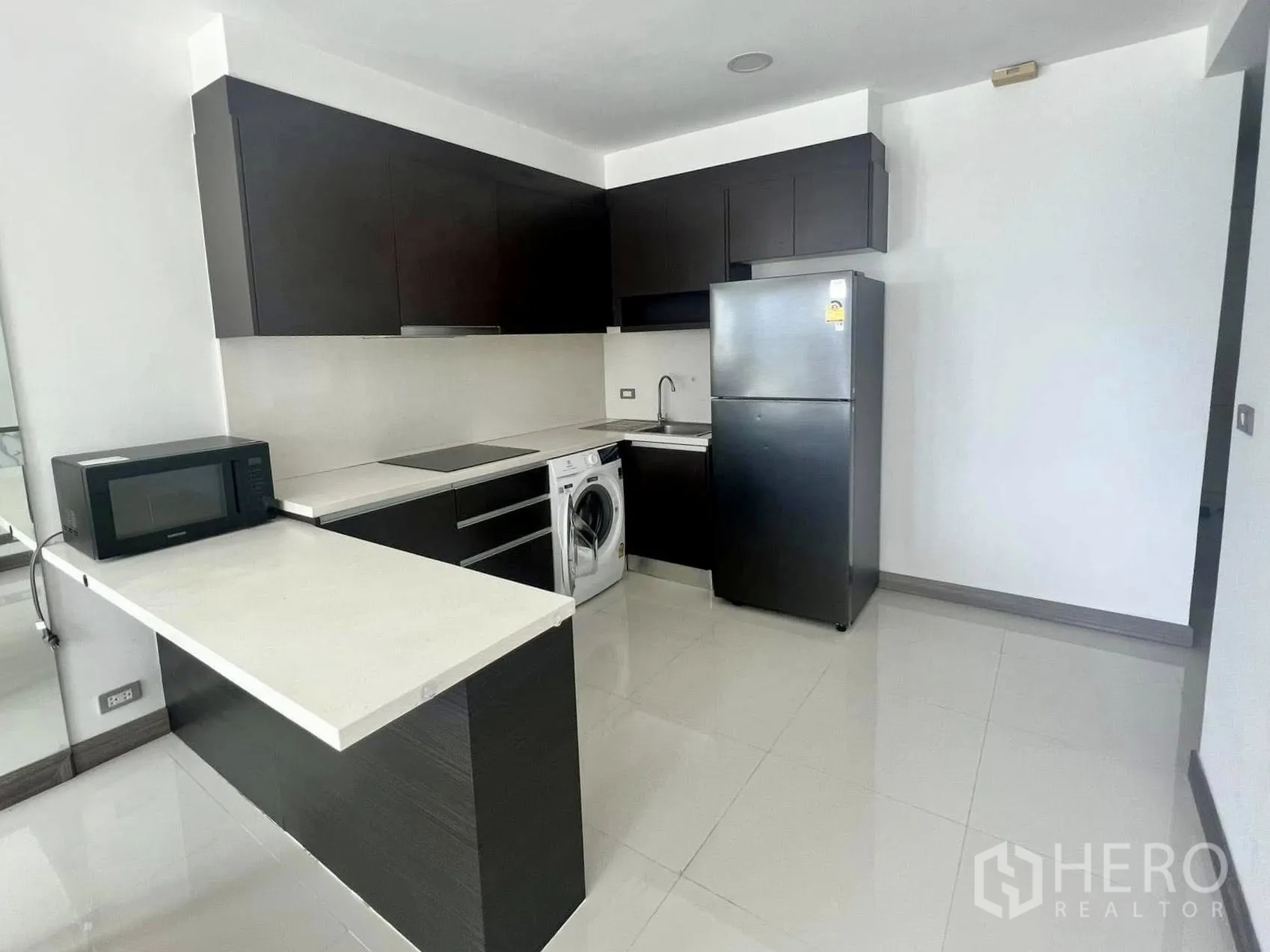 คอนโด ให้เช่าในWatthana, Bangkok - ครัวรูปตัวแอลสมัยใหม่ มีตู้เย็น ไมโครเวฟ เตาไฟฟ้า และเครื่องซักผ้า