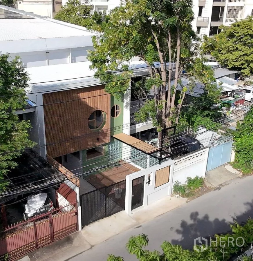 Townhouse for rent in Watthana, Bangkok - Aerial view of the townhouse and neighborhood with a large shade tree, front deck and gated entrance.
