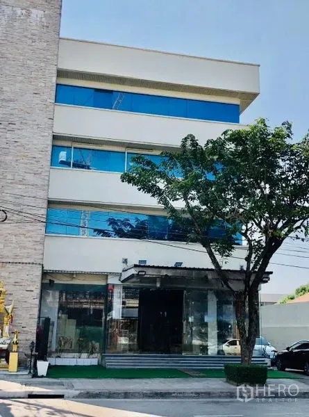 店屋 出租在Lat Phrao, Bangkok - 商铺外立面街景，镜面窗、台阶入口与树荫。