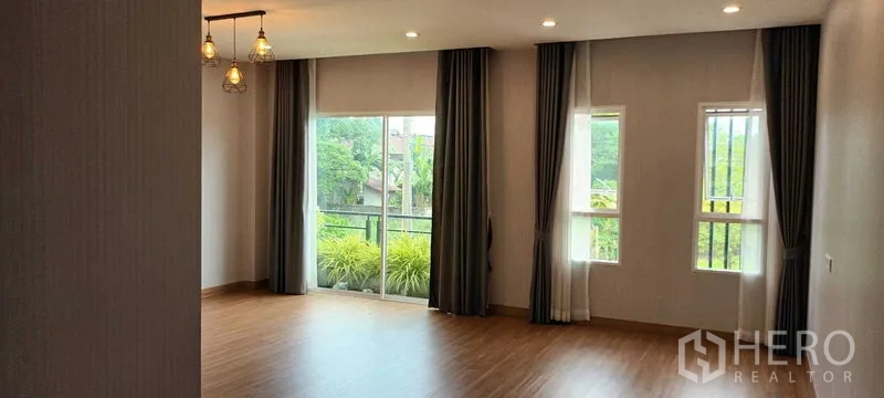 Townhouse for rent or sale in Saphan Sung, Bangkok - Sunlit bedroom with wood flooring, full-height windows and balcony access.