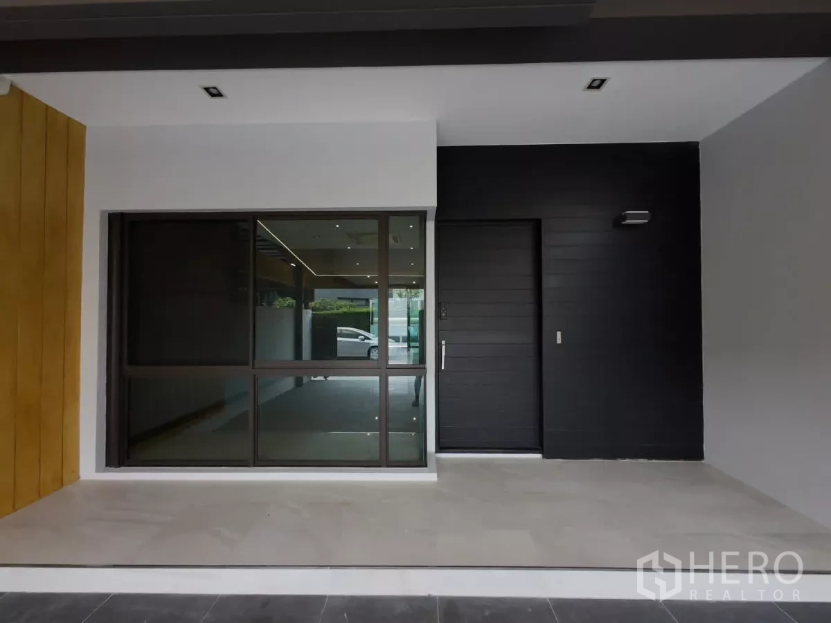Townhouse for rent or sale in Lat Phrao, Bangkok - Front entry with black door and large sliding glass window.
