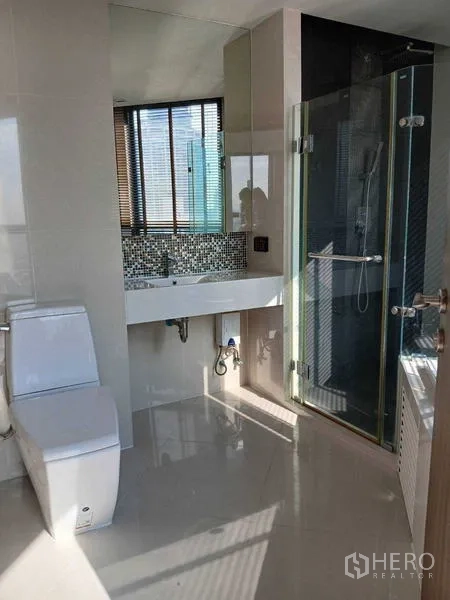 Condominium for rent - Bright bathroom featuring glass shower enclosure, vanity and toilet.