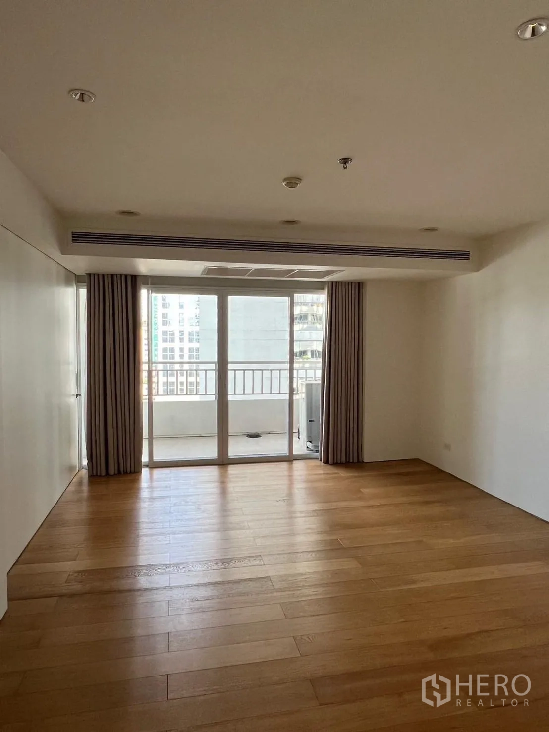 Condominium for rent or sale in Sathon, Bangkok - Large bedroom with wide plank wood floor, balcony doors and city view.