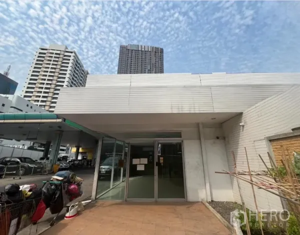 零售空间 出租在Khlong Toei, Bangkok - 低层店铺立面配宽檐，背景可见高楼。