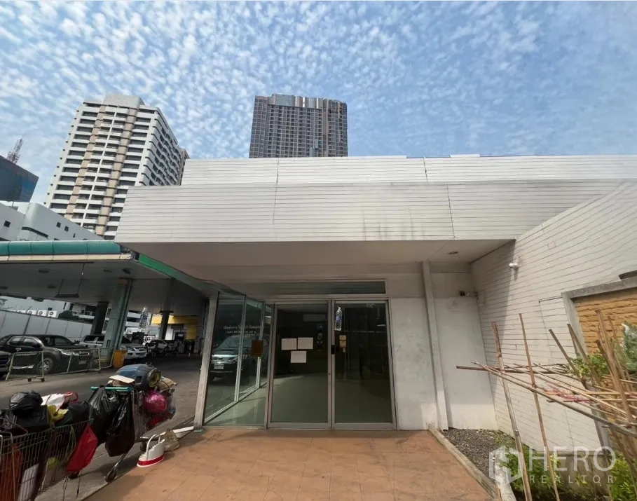 零售空间 出租在Khlong Toei, Bangkok - 低层店铺立面配宽檐，背景可见高楼。