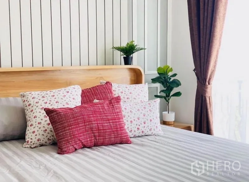 Townhouse for rent in Prawet, Bangkok - Close-up of bed with patterned cushions and potted plants by the window.
