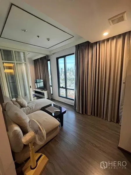 คอนโด ขายในRatchathewi, Bangkok - มุมห้องนั่งเล่นพร้อมผ้าม่านทึบ พื้นไม้ และหน้าต่างสูงมองเห็นวิวกรุงเทพฯ