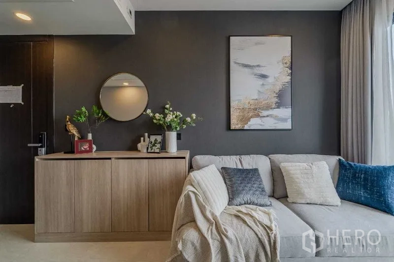 Condominium for rent in Pathum Wan, Bangkok - Contemporary living space with sectional sofa, console cabinet and abstract wall art.