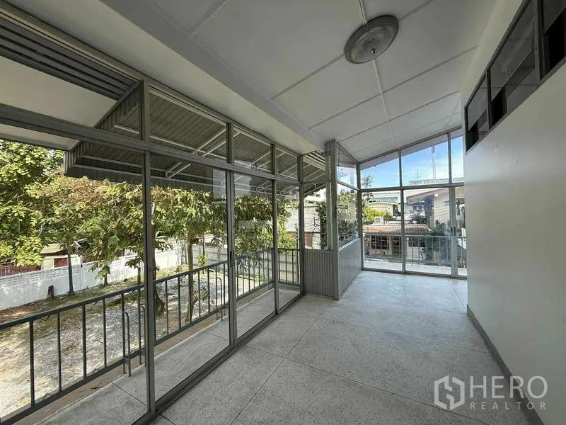 Detached House for rent in Watthana, Bangkok - Glass‑enclosed sunroom and balcony overlooking trees and the neighborhood.