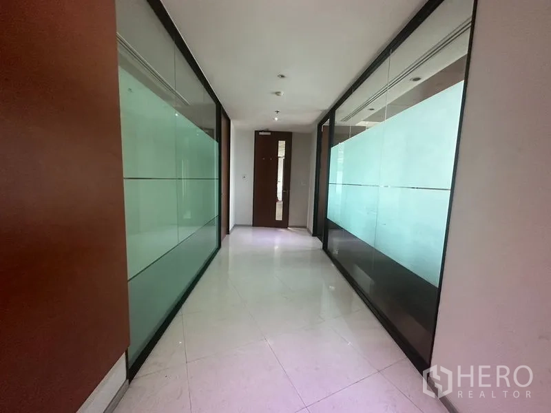 办公空间 出租在Khlong Toei, Bangkok - 明亮走廊，瓷砖地与玻璃墙通向各办公室。