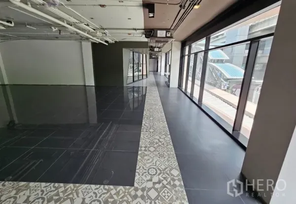 Retail Space for rent in Bang Rak, Bangkok - Retail space featuring floor-to-ceiling windows facing a skywalk, patterned tile border, and dark porcelain flooring.