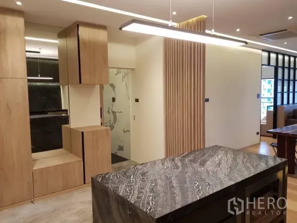 Condominium for rent in Bang Rak, Bangkok - Kitchen island facing a corridor with wood slat feature wall and sleek storage cabinets.