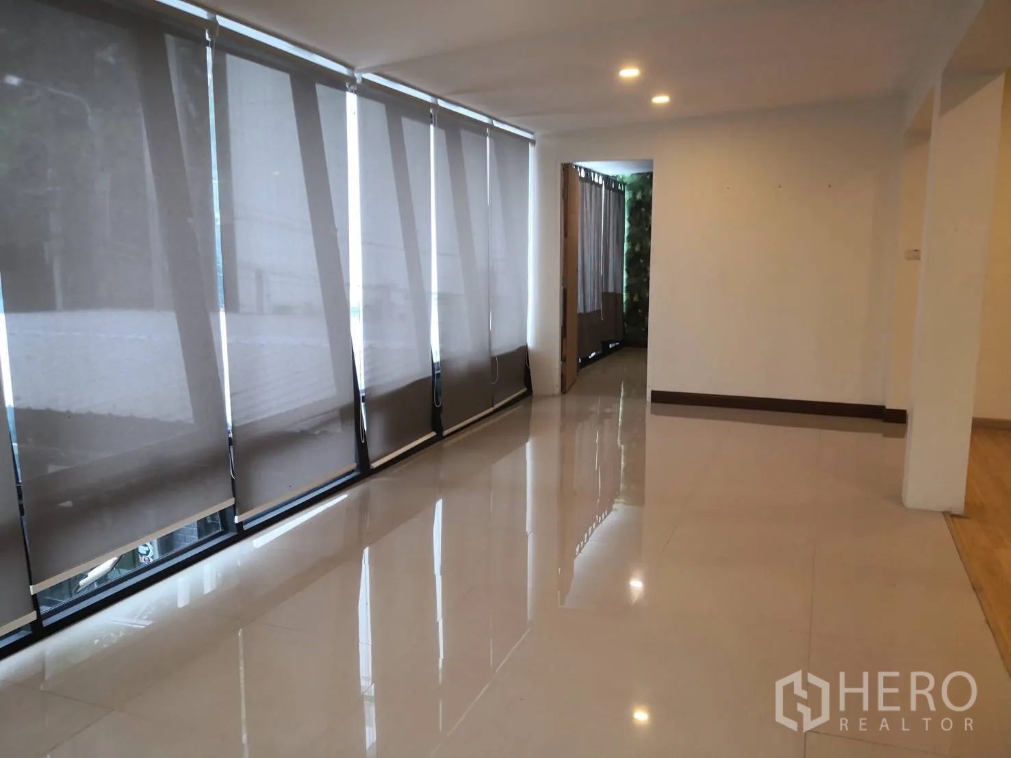 Detached House for rent in Watthana, Bangkok - Open-plan room with glossy tiled floors, recessed lighting, and full-height windows with blinds.